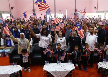Nie Ching (tengah) mengibarkan Jalur Gemilang pada program Madani Kita di Dewan Raya Taman Desa, Skudai hari ini.