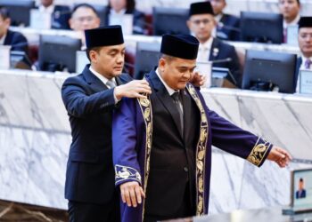 ONN HAFIZ Ghazi (kiri) memakaikan jubah kepada Zahari Sarip selepas dilantik sebagai Speaker DUN Johor.