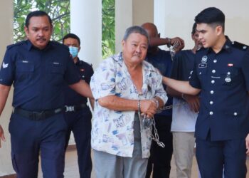 OOI Hock Wah (tengah) diiringi oleh anggota polis ketika dihadapkan ke Mahkamah Sesyen George Town, Pulau Pinang atas pertuduhan sengaja menyebabkan kecederaan parah terhadap jirannya yang berusia 80 tahun dengan menggunakan sebatang besi, Ahad lalu.-UTUSAN/DANIAL SAAD