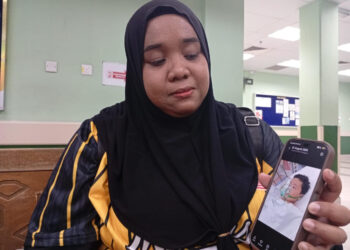 PUTERI Anis Athirah Wan Rosli menunjukkan gambar Che Ku Muhammad Khairul Amir Che Ku Mohd Khairul Azlan yang kini dirawat di Jabatan Kecemasan HSNZ, Kuala Terengganu, Terengganu. - UTUSAN/ ERMA YUSNIDA JUSOH