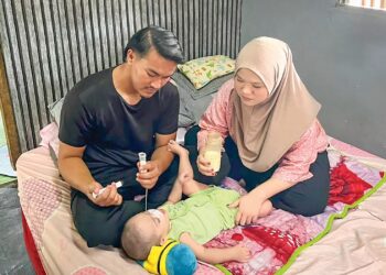 ABDULLAH Hashim dan Siti Nur Najwa Zamrifaizal memberikan 
susu khas kepada Muhammad Nuh Alfateh sebagai sebahagian keperluan pemakanannya di Kampung Balok, Kuantan, Pahang semalam. – UTUSAN/DIANA SURYA ABD WAHAB