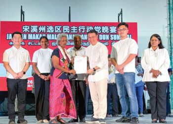 NGA Kor Ming menyampaikan geran tanah kepada penerima pada majlis Jamuan Makan Malam anjuran DAP DUN Sungkai di Tanjung Malim, semalam.