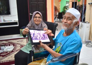 SYUKRI Abdullah (kanan) dan  isterinya, Lebar Nopiah, 70, menunjukkan gambarnya semasa ditugaskan di Somalia  ketika ditemui di rumahnya di Kampung Jelempok, Arau, Perlis.-UTUSAN/ASYRAF MUHAMMAD