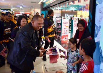 ABU Bakar Hamzah (kiri) mengagihkan Jalur Gemilang kepada orang ramai semasa Program Info On Wheels di Kangar Jaya Mall, Perlis, hari ini. -UTUSAN/ASYRAF MUHAMMAD