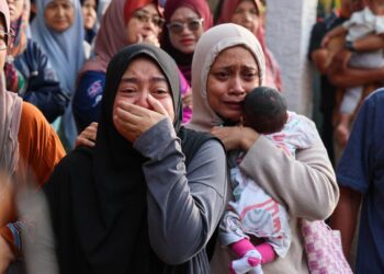 NUR Izzah Ahmad (kiri) tidak dapat menahan kesedihan selepas suami dan anaknya, Amirul Fahmi Wan Jusoh, 40, dan Rehan Yusuf maut dalam kebakaran di Kampung Tok Jembal, Kuala Nerus, Terengganu. - UTUSAN/PUQTRA HAIRRY