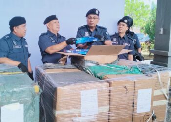 MOHD. Hisham Mohd. Nor (dua dari kanan) memeriksa rokok putih seludup yang dirampas di Pejabat JKDM Rantau Panjang, Kelantan. - UTUSAN/ROHANA ISMAIL