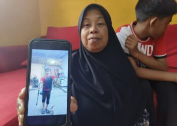 NORHABIBI Jaafar menunjukkan gambar anaknya yang maut terkena renjatan elektrik semasa mahu mengambil mata kail tersangkut pada wayar elektrik di Kampung Langgar, Kota Bharu, Kelantan.-UTUSAN/YATIMIN ABDULLAH.