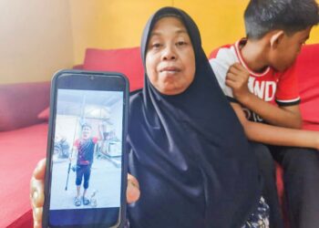 NORHABIBI Jaafar menunjukkan gambar anaknya yang maut terkena renjatan elektrik ketika mahu mengambil mata kail tersangkut pada wayar elektrik di Kampung Langgar, Kota Bharu, Kelantan. – UTUSAN/YATIMIN ABDULLAH