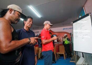 AHLI keluarga penumpang yang terjejas membaca perkembangan terkini mengenai operasi menyelamat feri Virgo Transport 8 di sebuah papan putih di Pelabuhan Trisakti Bandarmasih, Banjarmasin. - AFP