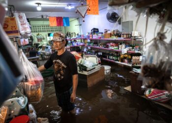 PEMILIK kedai runcit berdiri di dalam premisnya yang ditenggelami air di daerah Bang Kapi, Bangkok.- AFP