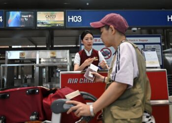 SEORANG penumpang mendaftar masuk di kaunter penerbangan Air China di Lapangan Terbang Antarabangsa Beijing Capital.-AFP