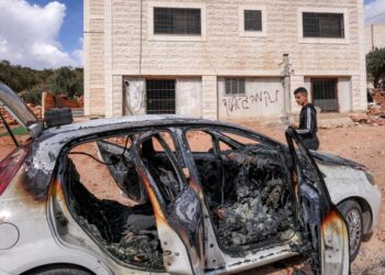 SEORANG pemuda Palestin memeriksa beberapa kenderaan yang musnah selepas serangan oleh peneroka haram Israel di kampung al-Mughayyir di Tebing Barat.-AFP