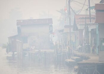 SEORANG lelaki duduk di tepi Sungai Kapuas ketika asap tebal dan jerebu menyelubungi bandar Pontianak di Kalimantan Barat.- AFP