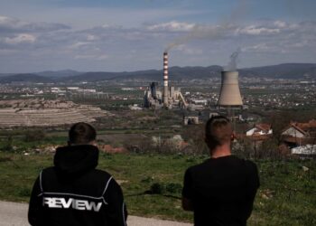 DUA lelaki berdiri di sebuah kawasan lapang menghadap loji janakuasa arang batu Kosovo berhampiran bandar Obilic.-AFP