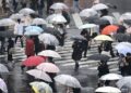 PEJALAN kaki membawa payung ketika melintasi jalan dalam hujan di daerah Shibuya, Tokyo.-AFP