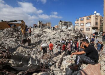 PENDUDUK Palestin melihat anggota Pertahanan Awam menggali runtuhan Menara Al-Muhandisin di tengah Gaza yang musnah akibat serangan Israel menyasarkan Hamas. - AFP