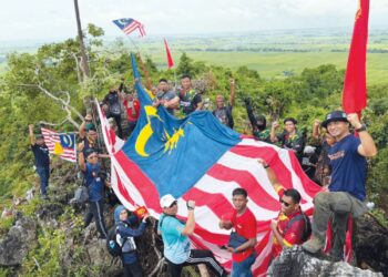 SEBAHAGIAN komuniti Bukit Hantu bergambar bersama Jalur Gemilang bersaiz besar yang dipasang di puncak bukit sempena Hari Malaysia di Kodiang, Kubang Pasu.