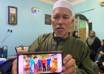 KAMARUDIN Salleh menunjukkan gambar Dr. Ainul Baroah (dua kiri) ketika ditemui di Kampung Baung, Kota Bharu, Kelantan-UTUSAN/YATIMIN ABDULLAH.