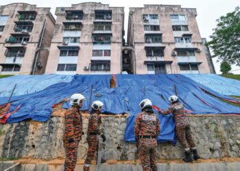 ANGGOTA bomba menutupi kawasan tanah runtuh dengan kanvas di Flat Bandar Damai Perdana, Bandar Tun Hussein Onn, semalam.