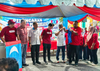 Amirudin Shari memakaikan jaket kepada seorang petugas pada Pelancaran Jentera Pilihan Raya PKR Masjid Tanah di Lendu malam tadi.
