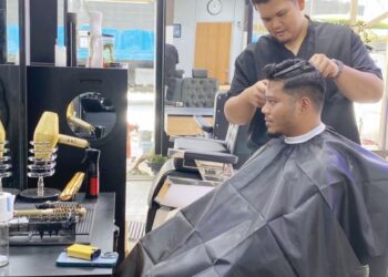 NUR ALLIF SHAMSUDDIN (berdiri) mampu menjana pendapatan kasar mencecah RM10,000 sebulan hasil perniagaan Kedai Gunting Allif yang telah beroperasi selama 10 tahun di Kedai Desa, Dataran Amanjaya Temoh, Tapah.