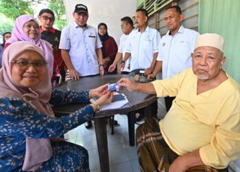 HASHIM Hassan menerima Kad Kesihatan Kasih Makmur yang disampaikan Sabariah Saidan (kiri) ketika mengadakan Jelajah Kuala Lipis. - MINGGUAN/SHEIKH AHMAD RAZIF