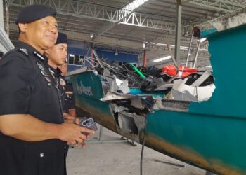 AB. RAHAMAN Arsad (kiri) melihat keadaan salah sebuah bot yang terlibat dalam kemalangan maut di Kuala Sungai Mersing, malam tadi.