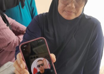 SUHAILAH Mohd. Sanin menunjukkan gambar adiknya, Mohamad Sohaizi Mohd. Sanin yang maut dalam kemalangan melibatkan dua buah bot di Kuala Sungai Mersing, malam tadi.