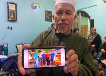 KAMARUDIN Salleh menunjukkan gambar anaknya, Dr. Ainul Baraah (dua kiri) ketika ditemui di Kampung Baung, Kota Bharu, Kelantan baru-baru ini.
