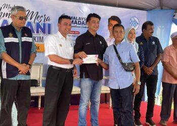 MUHAMMAD Faiz  Fadzil (tengah) menyampaikan sumbangan bantuan nelayan kepada penerima di Pejabat Penghulu Matang hari ini.- UTUSAN/WAT KAMAL ABAS
