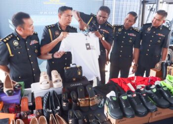 S. JEGAN (tengah) bersama sebahagian daripada barangan berjenama tiruan yang dirampas semasa program pelupusan barangan tersebut di Kompleks Penyimpanan Ekshibit KPDN di Jalan Bukit Minyak, Bukit Mertajam, Pulau Pinang.-UTUSAN/DANIAL SAAD
