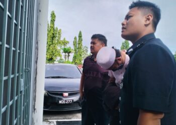 TERTUDUH semasa dibawa oleh polis untuk prosiding perbicaraan di Mahkamah Majistret Kuala Krai, Kelantan. - UTUSAN/ROHANA ISMAIL