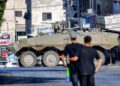 BEBERAPA orang melihat sebuah kereta kebal Israel di Tebing Barat. - AFP