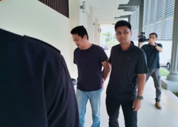 MOHD. Faizal Mat Yusoh (kiri) semasa dibawa polis untuk prosiding perbicaraan di Mahkamah Seksyen Pasir Mas, Kelantan. -  UTUSAN/ROHANA ISMAIL