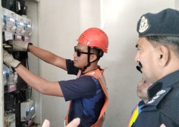 S. SARAVANAN melihat kakitangan TNB memotong bekalan elektrik di sebuah premis di Simpang, Taiping hari ini. - UTUSAN/WAT KAMAL ABAS