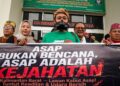 ANGGOTA Gabungan Nafas Kalbar memegang sepanduk mengecam isu kebakaran hutan dan  jerebu sebagai jenayah di luar Mahkamah Daerah Pontianak, Kalimantan Barat.-AFP