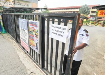 SEORANG pengawal keselamatan menutup pagar yang telah ditampal notis penutupan sekolah akibat jerebu di SMK Bandar Baru Uda, Johor Bahru, Johor, semalam. – UTUSAN/RAJA JAAFAR ALI