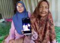 NORIAH Yusoff (kanan) menunjukkan gambar Allahyarham Noor Atirah Yacob dan suaminya yang maut dalam nahas di Jalan Sungai Buloh berhampiran susur masuk ke Sierramas, Petaling Jaya, Selangor petang semalam.