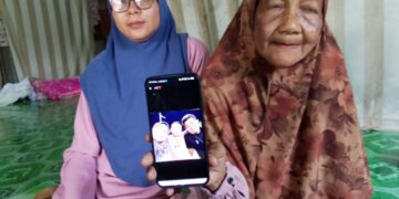 NORIAH Yusoff (kanan) menunjukkan gambar Allahyarham Noor Atirah Yacob dan suaminya yang maut dalam nahas di Jalan Sungai Buloh berhampiran susur masuk ke Sierramas, Petaling Jaya, Selangor petang semalam.