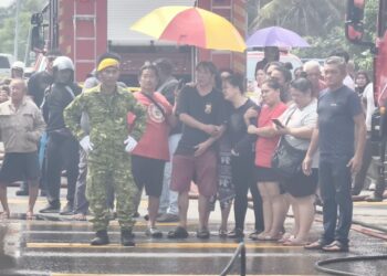KIONG (tengah) dan isterinya (empat dari kanan) melihat operasi memadam kebakaran rumah yang mengorbankan dua anak perempuan mereka di Kampung Koh, Sitiawan hari ini.