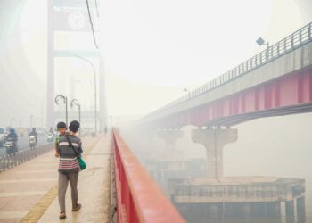 SEORANG lelaki mendukung seorang kanak-kanak ketika berjalan di Jambatan Ampera, Palembang, Sumatera Selatan. - AFP