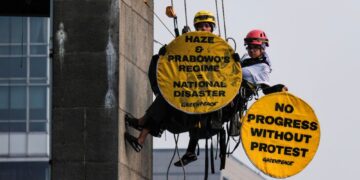AKTIVIS Greenpeace Indonesia yang bergayut pada Patung Selamat Datang di Bulatan Hotel Indonesia memegang sepanduk membantah jerebu di Jakarta semalam. - AFP.