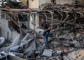 SEORANG lelaki membawa tong gas di celah runtuhan bangunan yang mengalami kerosakan teruk susulan serangan Israel ke atas sebuah pangsapuri kediaman di kawasan kejiranan Rimal, Gaza City, semalam.- AFP