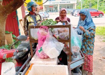 PENDUDUK kampung membeli barangan keperluan daripada Mat Junoh Latif, penjaja motosikal roda tiga di Kampung Penambang, Kota Bharu, Kelantan. – UTUSAN/ ROSLIZA MOHAMED