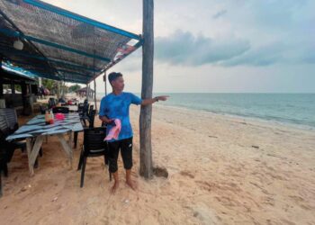 ZULKIFLI Deraman menunjukkan jarak laut yang kira-kira 10 meter sahaja dengan kedai celup tepungnya di Kampung Pachakan, Besut, Terengganu. – UTUSAN/WAN ZURATIKAH IFFAH WAN ZULKIFLI