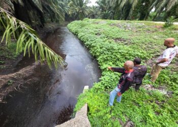 PENDUDUK menunjukkan air parit yang tercemar dipercayai daripada sisa buangan kilang kelapa sawit di Langkap di Pasir Salak, Perak  - UTUSAN/AIN SAFRE BIDIN