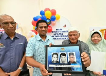 PAHANG Awang Mohamad (dua dari kanan) menunjukkan gambar kad pengenalannya bermula sejak berusia 12 tahun dan sehingga kini di Pejabat JPN Pekan, Pahang. – UTUSAN/SHAIKH AHMAD RAZIF