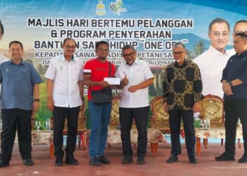 RASHIDI Zinol (tiga dari kanan) menyerahkan bantuan kepada petani pada majlis hari bertemu pelanggan dan penyaluran bantuan sara hidup kepada petani dan pesawah untuk daerah Barat Daya di daerah Balik Pulau, Pulau Pinang semalam.-UTUSAN/SAFINA RAMLI