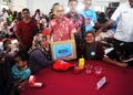 FAHMI Fadzil menyampaikan kotak Sejahtera Madani kepada seorang pendudukan pada program PMK Paya Rumput@Tangga Batu di Krubong.