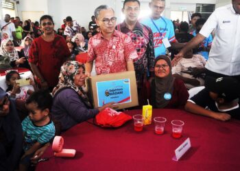 FAHMI Fadzil menyampaikan kotak Sejahtera Madani kepada seorang pendudukan pada program PMK Paya Rumput@Tangga Batu di Krubong.